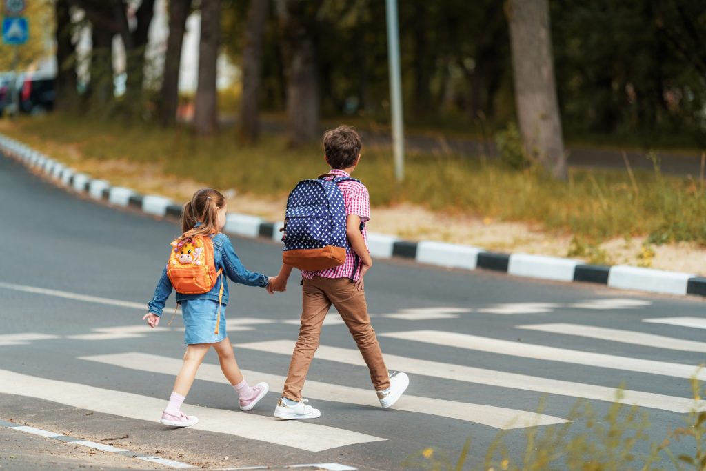 Niños cruzando paso de cebra para coger el bus de linecar para ir al colegio