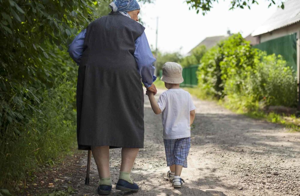 Abuela caminando junto a niño por camino en pueblo linecar